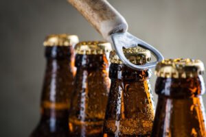 Brown ice cold beer bottles with water drops and old opener